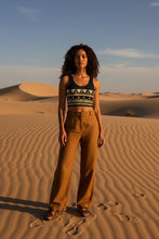 Load image into Gallery viewer, Melodia Gallery black cotton crop top with Nile Bloom pattern, lotus motifs, boho style. Model in desert.