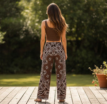Load image into Gallery viewer, Melodia Gallery unisex brown bandana print wide leg pants made of cotton and elastane.
