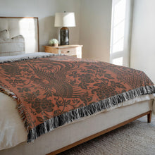 Load image into Gallery viewer, Melodia Gallery rust-colored 100% cotton woven blanket with a dark grey phoenix and floral pattern and fringed edges.
